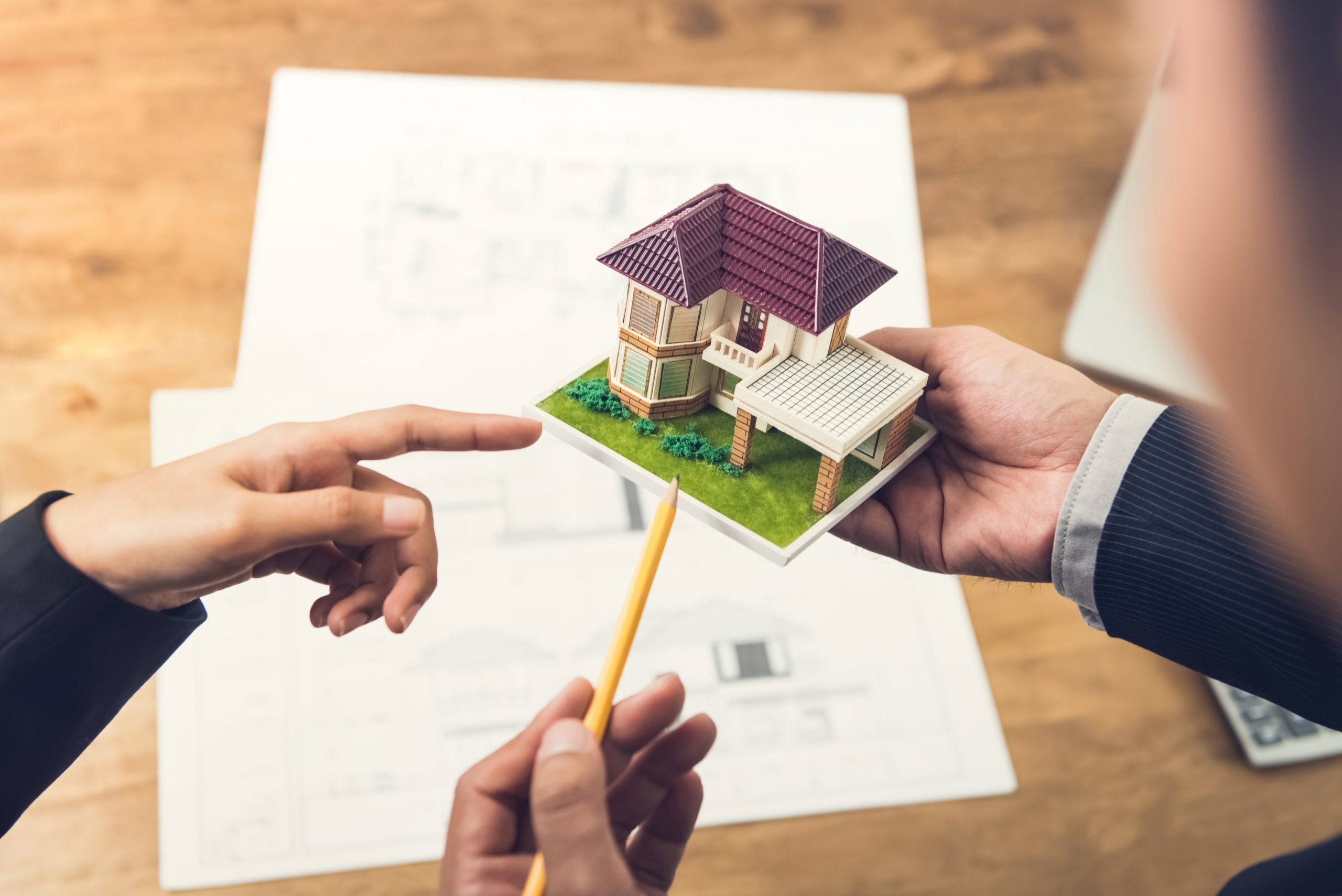 Housing developer agent holding an architectural model and explaining concept to client or architect for real estate development.