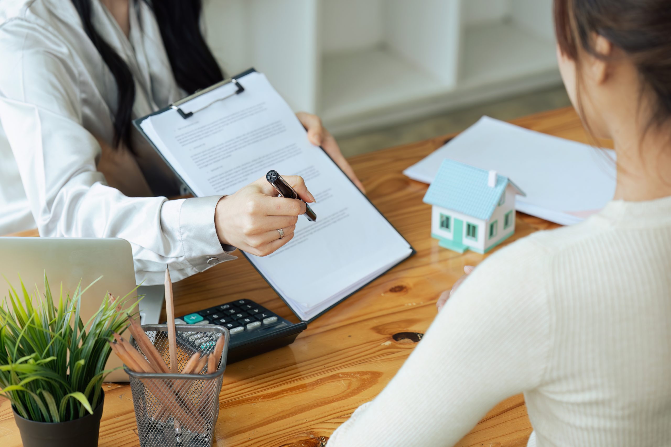 Real estate broker agent presenting and consult to customer to decision making sign insurance form agreement, home model, concerning mortgage loan offer for and house insurance..